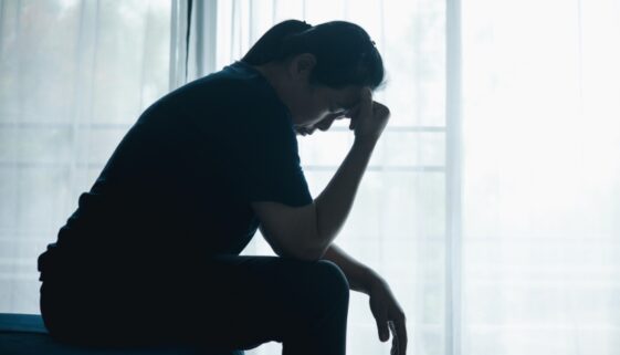 Woman resting her hand on forehead with a grey filter.